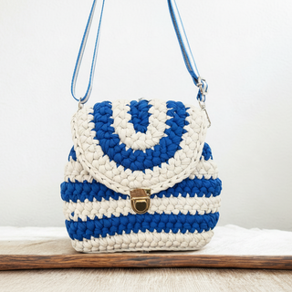 Blue and white crocheted handbag with a gold clasp on a wooden surface.
