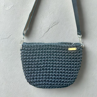 Blue textured handbag with a gold tag on a light gray background