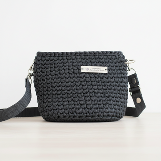 A small handmade crochet crossbody bag in black, made from polyester braided cord.