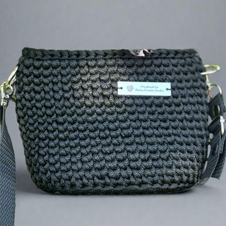 A black crochet handbag with a label that reads 'Handmade by Alpine Crochet Studio, LLC'.