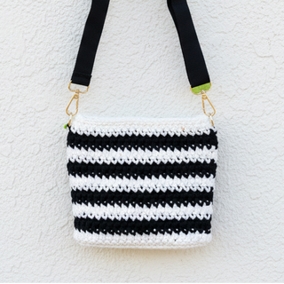 Black and white striped crochet bag with a strap on a textured white background