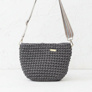 Brown textured handbag with a strap on a neutral background