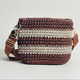 Crocheted bag with brown and beige stripes and a leather strap on a light gray background