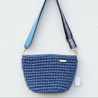 Blue crochet bag with a strap on a gray surface