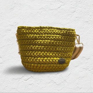 A handmade crochet crossbody bag in a golden lime color, with visible texture and a brand tag.