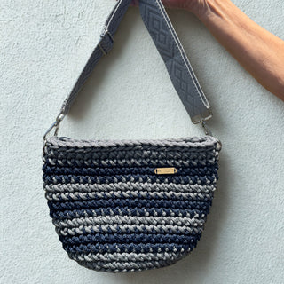Woven handbag with a strap on a light gray background