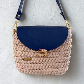 Handbag with blue top section and beige crochet body on a light gray background