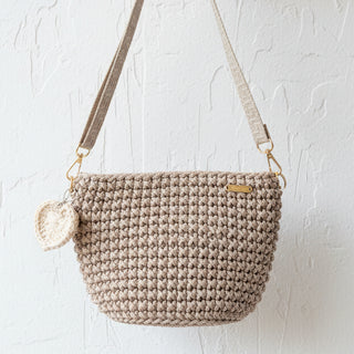 Beige crochet handbag with a matching pouch on a textured surface