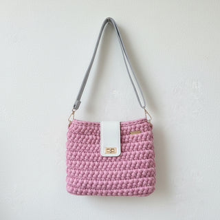 Pink textured handbag with a white strap on a light gray background