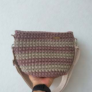 Handmade crochet bag with a gradient pattern held against a plain background