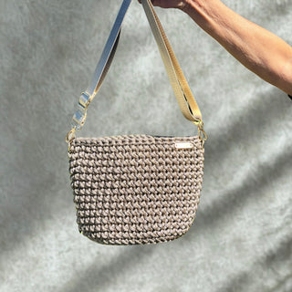 Woven handbag held by a person against a neutral background