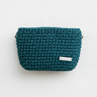 A handmade crochet crossbody bag in a peacock blue color.
