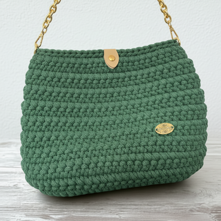 Green textured handbag with a gold clasp on a light surface.