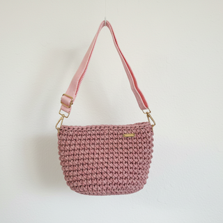 Pink crochet handbag with a strap on a light background