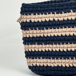 Navy and beige striped woven basket on a light gray background