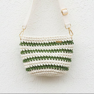 Crochet green and white bag with a strap on a light background