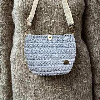 Light blue woven crossbody bag on a textured brown background