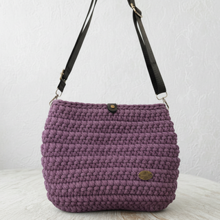 Purple knitted handbag with a strap on a light surface and light gray background