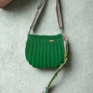 Green knitted bag with a floral-patterned strap on a light gray background