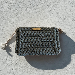 Textured pouch with pom-poms on a light gray background