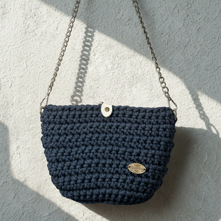 Navy blue woven handbag with a strap on a textured gray surface
