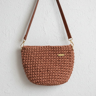 Brown woven handbag with a gold clasp on a light gray background