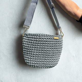 Gray crochet handbag with a strap on a light gray background