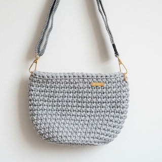 Gray crocheted handbag with a gold clasp on a light background