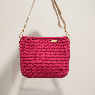 Pink woven handbag with a gold clasp on a light background
