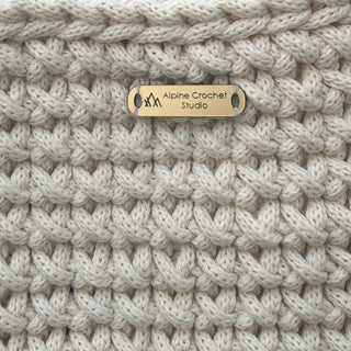 Close-up of a textured blanket with a brand tag, outdoors.