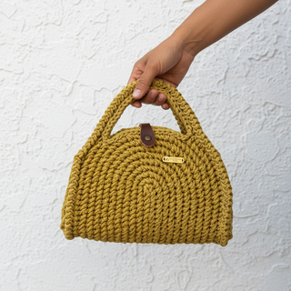 Hand holding a mustard yellow knitted handbag against a white textured background
