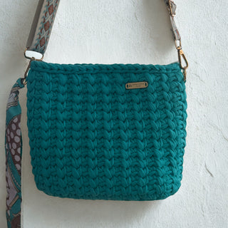 Teal knitted bag with a strap on a white background