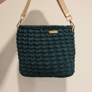Green woven handbag with a gold strap on a beige background