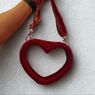 Red heart-shaped crochet purse held by a hand against a white background