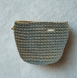 Crocheted pouch with a brand label on a light gray background