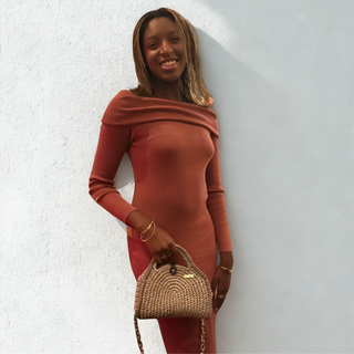 Woman in a rust-colored dress holding a crochet handbag against a light background