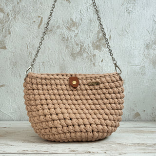 Beige crochet handbag with a brand label on a textured surface.