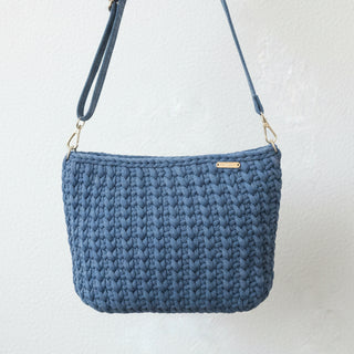 Black crocheted handbag on a textured surface with a neutral background