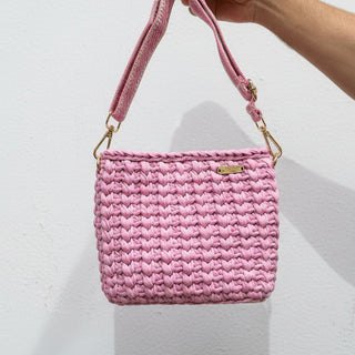 Pink woven handbag with a strap on a light background
