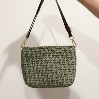 Green woven handbag with a gold clasp on a light background