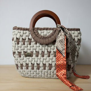 Handmade crochet shoulder bag in brown and beige with wooden handles and a fabric strap.